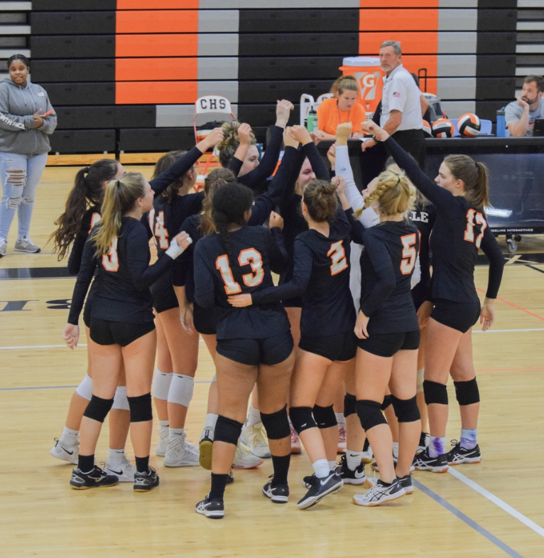 The volleyball team huddles together in a home game. 