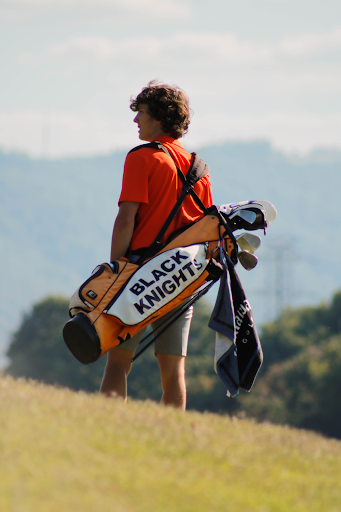 Junior,  Davis Ramsey, carrying his clubs on the golf course.
